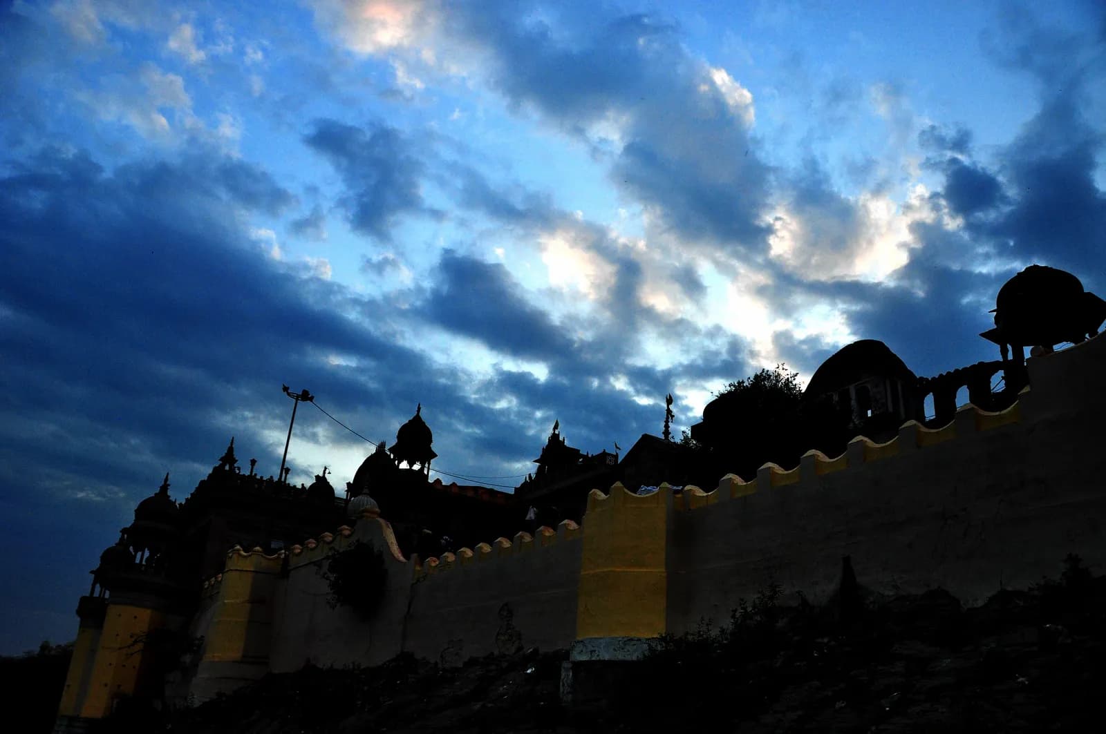 The Barsana temple walls and spires silhouetted along the crest of Bhanugarh hill against a blue evening sky